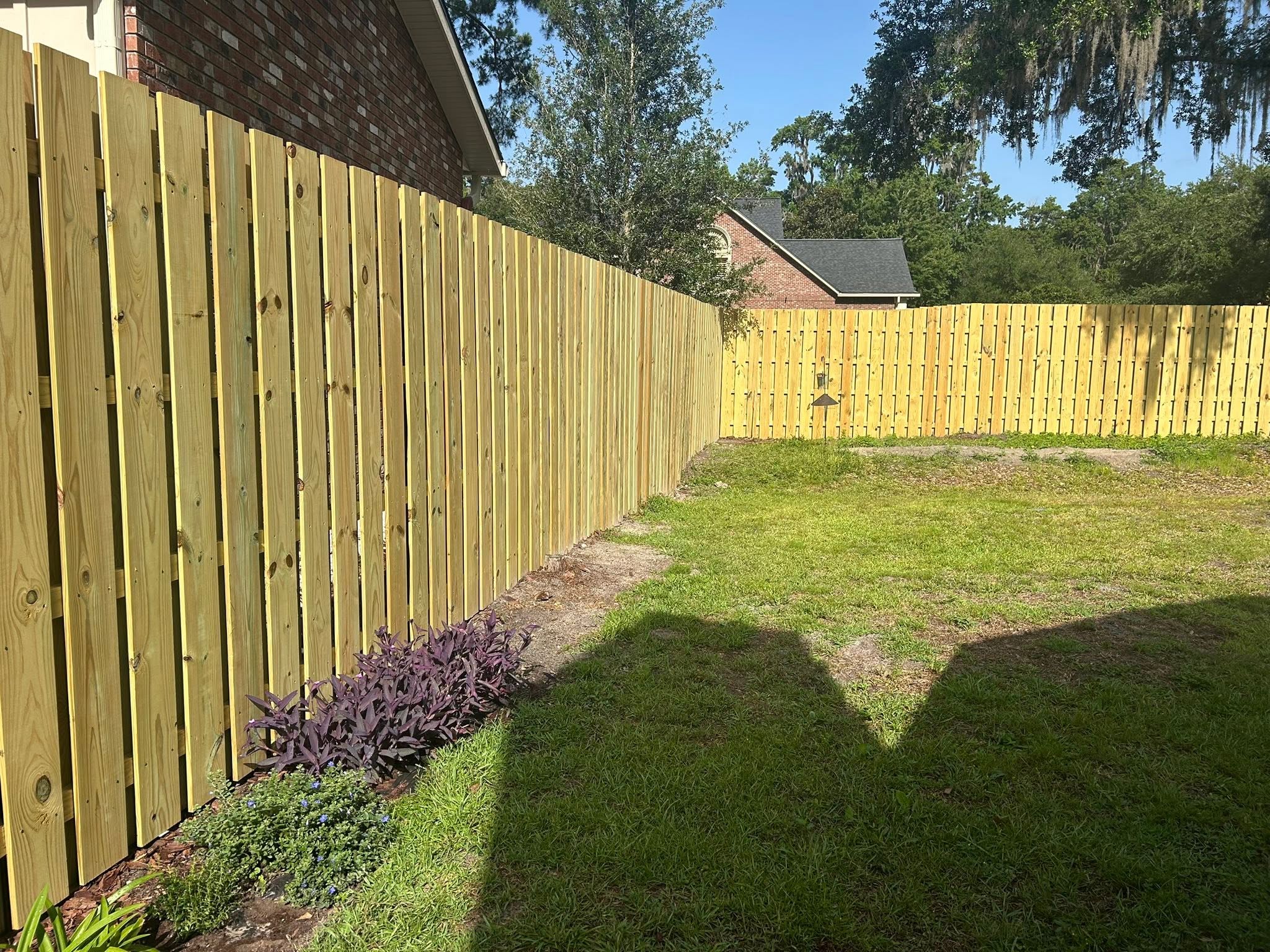 New wood privacy fence enclosing a sunny backyard